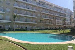 a swimming pool in front of a large apartment building at Appartement Cosy Bouznika, plage proche in Bouznika