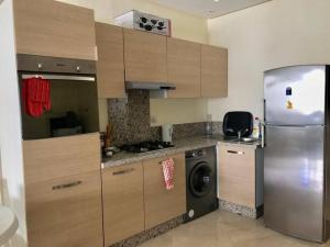 a kitchen with a refrigerator and a washing machine at Appartement Cosy Bouznika, plage proche in Bouznika