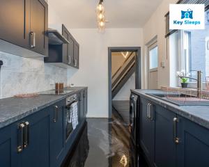 a kitchen with navy blue cabinets and a staircase at Stylish House By Keysleeps Central&Free Parking&Games Room At St Helens in Saint Helens