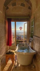 a large bath tub in a bathroom with a window at Takaev Cave House in Uçhisar