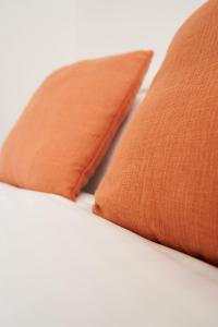 dwie pomarańczowe poduszki siedzące na łóżku w obiekcie Rotherwood Apartment w Glasgow