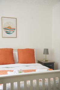 a white crib with orange pillows in a bedroom at Rotherwood Apartment in Glasgow