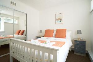 a white bedroom with a crib and a mirror at Rotherwood Apartment in Glasgow