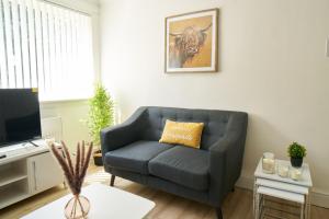 a living room with a blue couch and a television at Rotherwood Apartment in Glasgow