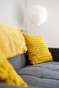 a couch with two yellow pillows on it at Rotherwood Apartment in Glasgow +24 photos