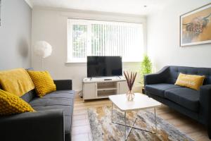a living room with two couches and a tv at Rotherwood Apartment in Glasgow