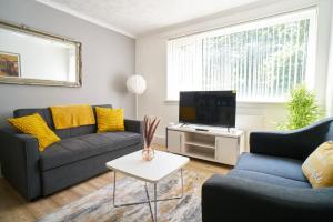 a living room with two couches and a tv at Rotherwood Apartment in Glasgow