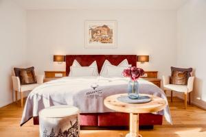 Hotel Waldhaus am See في فالبيلا: غرفة نوم بسرير وطاولة مع إناء من الزهور