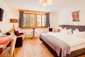 1 dormitorio con 1 cama blanca grande y escritorio en Hotel Waldhaus am See en Valbella