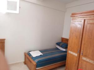 a small bedroom with a bed and a wooden cabinet at KHAOULA in Rabat