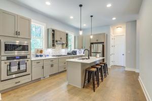 a kitchen with white cabinets and a island with bar stools at Quaint Newnan Vacation Rental Near State Park! in Newnan