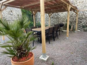 einen Holztisch und Stühle unter einer hölzernen Pergola in der Unterkunft Les Limicoles maison proche mer in Gouville-sur-Mer
