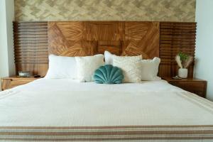 uma cama grande com almofadas brancas e uma cabeceira em madeira em Hotel Suite Luxe Sunset em Tijuana