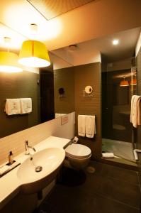een badkamer met een wastafel, een toilet en een spiegel bij Porto Trindade Hotel in Porto