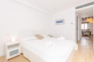 um quarto branco com uma cama branca com dois animais de peluche em Townhouse with puig de María view by home villas 360 em Pollença