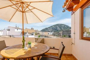 a wooden table with an umbrella on a balcony at Townhouse with puig de María view by home villas 360 in Pollença