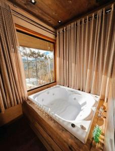a large bath tub in a room with a window at Sunset Serrano Chalés in Urubici
