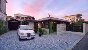 南城的住宿－ロフトが付いた沖縄古民家で寛ぎの時間を 懐かしくて新しい 海野24，停在房子前面的白色汽车