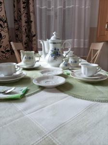 uma mesa com pratos e conjuntos de chá sobre ele em Kiskastély Apartman em Balmazújváros