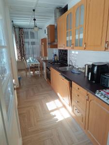 a kitchen with wooden cabinets and a wooden floor at Kiskastély Apartman in Balmazújváros