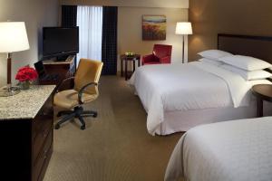ein Hotelzimmer mit 2 Betten, einem Schreibtisch und einem TV in der Unterkunft Sheraton Albuquerque Uptown by Marriott in Albuquerque