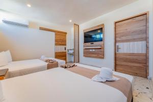 メリダにあるHotel Central Merida by Kaviaのベッド2台とテレビが備わるホテルルームです。