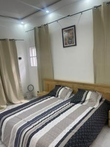 1 dormitorio con 1 cama con manta a rayas en Appartement Kekely en Lomé