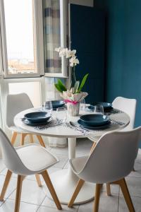 uma mesa de jantar branca com cadeiras brancas e pratos azuis em Ad un passo dal molo con 2 biciclette incluse em Viareggio