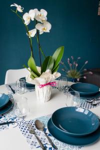 a table with blue plates and a vase with white flowers at Ad un passo dal molo con 2 biciclette incluse in Viareggio
