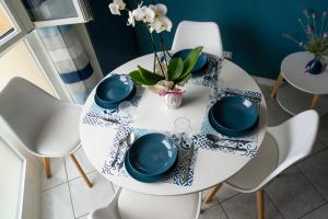 una mesa de comedor blanca con platos azules y blancos en Ad un passo dal molo con 2 biciclette incluse, en Viareggio