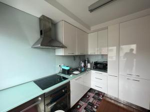 a kitchen with white cabinets and a stove top oven at Vela Marina, Costa Nova in Gafanha da Encarnação