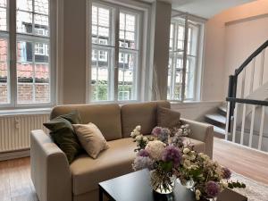 una sala de estar con sofá y flores en una mesa. en Ferienwohnung Marzipan - im Herzen der Altstadt, historisches Gebäude mit modernem Ambiente, W-LAN, en Lübeck