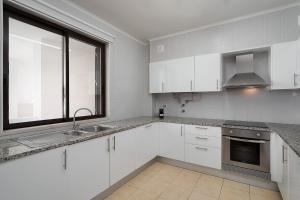 a kitchen with white cabinets and a sink and a window at Dream 2BDR Apartment W/Pool by LovelyStay in Alvor
