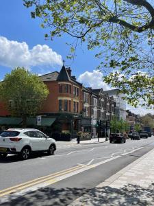 a white car driving down a city street with buildings at Chamberlayne Inn in London