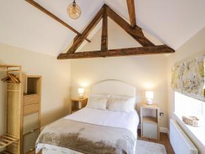 a bedroom with a white bed with a wooden ceiling at The Dairy in Nuneaton