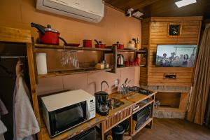 a kitchen with a microwave and a tv on a counter at Sunset Serrano Chalés in Urubici