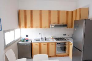 a kitchen with wooden cabinets and a stainless steel refrigerator at Casa Claire in San Vito lo Capo