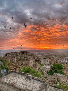 un gruppo di aquiloni che volano nel cielo al tramonto di Takaev Cave House a Üçhisar