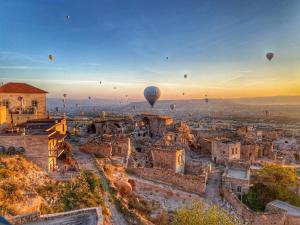 a group of hot air balloons flying over a city at Takaev Cave House in Uchisar
