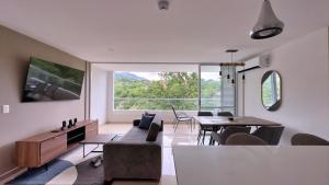 een woonkamer met een tafel en stoelen en een groot raam bij Stunning, Brand-new Apartment in Santa Fe de Antioquia