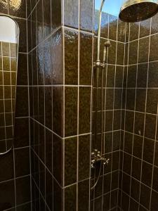 ducha con paredes de azulejos negros y cabezal de ducha en Aggershøj pensionat en Marstal