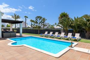 a swimming pool with chaise lounge chairs next to a resort at Hipoclub Villas, "Rosa" villa in Playa Blanca