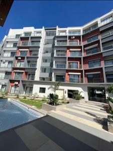 een groot appartementencomplex met een zwembad ervoor bij Aquaview Amina's rental apartment in Bijilo