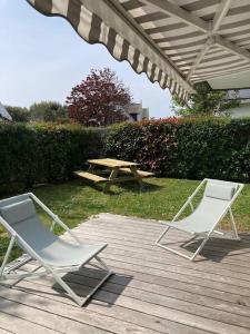 two chairs and a picnic table on a wooden deck at Le GLAZ * Grande plage & commerces à pied * Jardin in Carnac