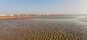 a beach with ripples in the sand and houses in the background at The Studio in Pevensey