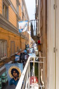 Un balcón de un edificio con banderas. en Napoli Napoli Rooms en Nápoles