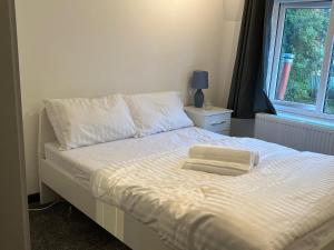 Una cama con sábanas blancas y una ventana en una habitación en Nano Rooms Accommodation en Coventry