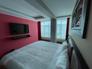 - une chambre avec un lit et une télévision à écran plat dans l'établissement R&N SHULLKAS SUITES, à Huancayo