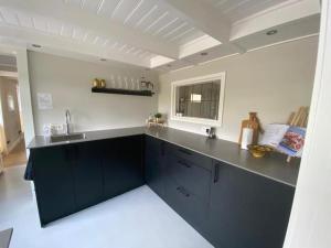 a kitchen with a black counter and a sink at Rusttheater, genieten van rust en ruimte in Reutum