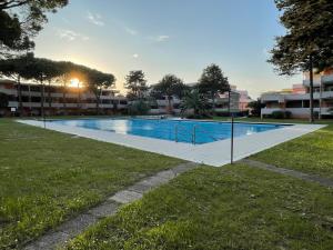 a swimming pool in a park with the sun setting at Residence Solarium Qua in Bibione